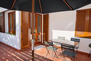 a patio with a table and chairs and an umbrella at Les cases del vent II in Calafat