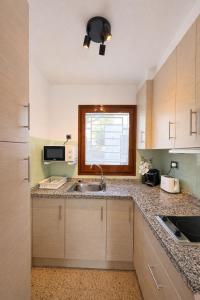 a kitchen with wooden cabinets and a sink and a window at Les cases del vent II in Calafat +12 photos