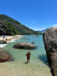 a man walking in the water at a beach at Xaveco hospedagem in Mangaratiba