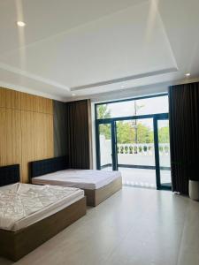 a bedroom with two beds and a large window at Signature in Ấp Vĩnh Lạc