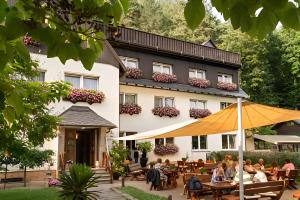 a hotel with people sitting at tables in front of a building at Pension Am Nationalpark in Stadt Wehlen