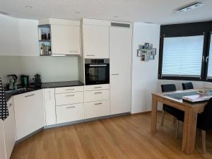 a kitchen with white cabinets and a table at Bergperle in Grächen