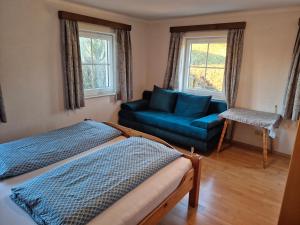 a bedroom with a blue bed and a couch at Ferienhof Edtmeier in Zell am Moos