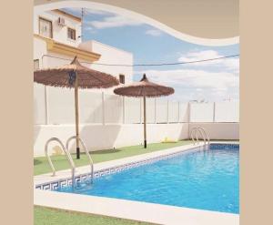 a swimming pool with two umbrellas next to a building at Casa Teuwisse in Torre-Pacheco