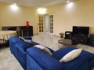 a living room with a blue couch and a table at Grand et chic appartement in Dakar