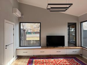 a living room with a flat screen tv and two windows at Ala-Archa Mountain House in Vorontsovskoye