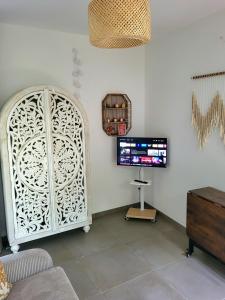 a living room with a white partition and a tv at Le Studio Joli in La Possession