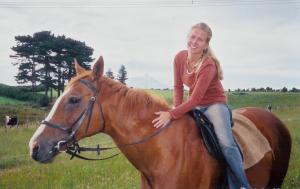 a young girl sitting on a horse in a field at Wheatly Downs Farmstay and Backpackers in Hawera