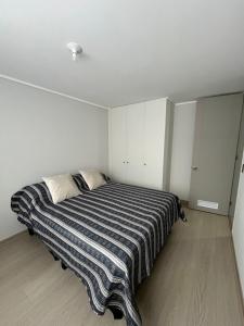 a bedroom with a large bed with a striped blanket at Departamento en Villarrica con Piscina y Estacionamiento Privado in Villarrica +16 photos