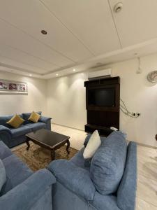 a living room with blue couches and a television at فيو المنسك in Abha