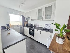 a kitchen with white cabinets and a potted plant at Ferienwohnung Sunset - Traumhafter Seeblick & Sauna in Steinhude in Wunstorf