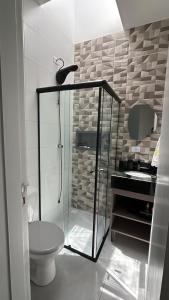 a bathroom with a glass shower and a toilet at Beach house in Matinhos in Matinhos