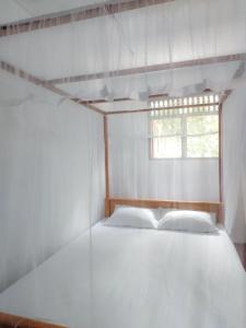 a white bed in a room with a window at Indrasiri Villa Midigama in Kumbalgama +8 photos