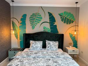 a bedroom with a bed with green leaves on the wall at Best Apartment Scheia in Suceava