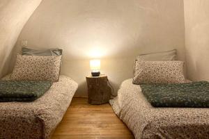 two beds in a room with a lamp on a table at Cévennes et Causse Mejean in Dargilan