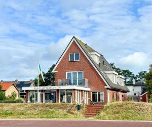 a large red brick house on top of a hill at Appartement met uitzicht over de Wadden Zee in Oost-Vlieland
