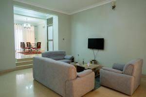a living room with two chairs and a tv at Kaze Consolidate Home Inn in Kigali
