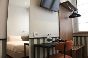 a room with a bed and a desk with a television at HÕMA Certosa District in Milan