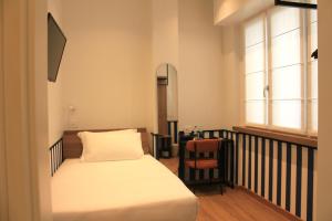 a small bedroom with a bed and a table at HÕMA Certosa District in Milan