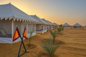 a row of tents in the desert with palm trees at Marwar Desert Camp Sam Jaisalmer in Sām