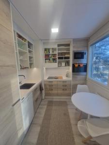 a kitchen with white cabinets and a table and a window at Haltijanmetsä in Kotka