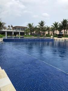 a large blue swimming pool with palm trees in the background at Wyndham garden villa 304 in Cam Lâm