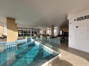 a large swimming pool with blue water in a building at Lavit 92 - Conforto, estilo e lazer com piscina e academia in Bauru
