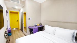 a bedroom with a white bed and a purple table at City Hotel Shymkent in Shymkent