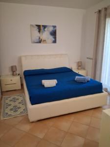 a bedroom with a bed with blue sheets and two towels at Casamare Roby in Tanaunella