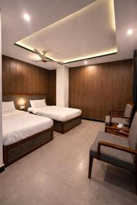 a hotel room with two beds and a chair at Hotel Noor Sky in Islamabad