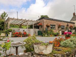 a garden in front of a brick building with flowers at Ffynnonlwyd Cottage - rural holiday cottage with hot tub in Llangynin