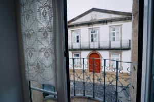 a window view of a building with a red door at Alojamento da Zá in Vila Pouca de Aguiar