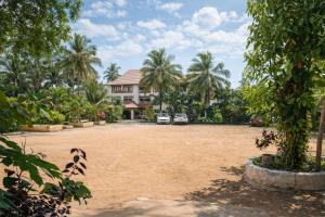 a large yard in front of a house with palm trees at Manan Beach Resort in Malpe