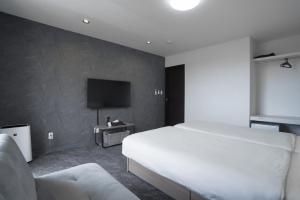 a bedroom with a white bed and a tv at Laon Inn Miyakojima in Miyako-jima