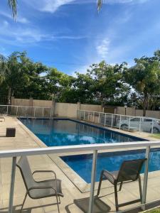 a swimming pool with two chairs next to a fence at Ap Hostel For You in Serra