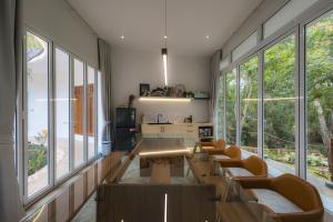 a living room with a table and chairs and windows at Mooncake house khaoyai in Ban Bung Toei