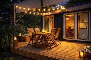 a wooden deck with a table and chairs and lights at Wisla66 Domki nad Wisłą Piotrawin in Piotrawin