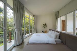 a bedroom with a bed and large windows at Mooncake house khaoyai in Ban Bung Toei