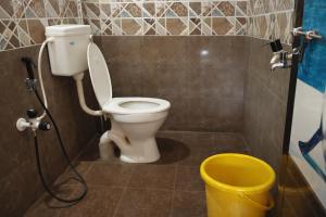 a bathroom with a toilet and a yellow bucket at Manan Beach Resort in Malpe