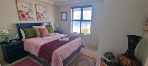 a bedroom with a bed with a pink blanket and a window at MaKarLi Blu in St. Helena Bay