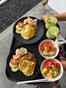 a tray with two plates of food and bowls of fruit at Uma Danu Villas Kintamani in Kubupenlokan
