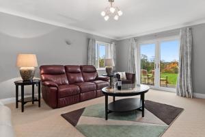 a living room with a leather couch and a table at Llais Y Mor - large holiday home close to the beach - sleeps 8 in Carmarthen