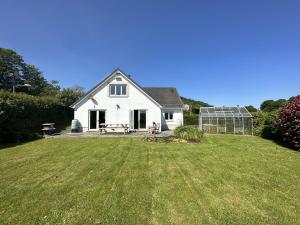 a white house with a greenhouse in the yard at Llais Y Mor - large holiday home close to the beach - sleeps 8 in Carmarthen