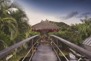 a wooden walkway leading to a resort with a thatch roof at Villa 1493 in Gustavia