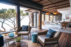 a porch with wicker chairs and tables with a view of the ocean at La Pépite Villa in Pointe d'Esny