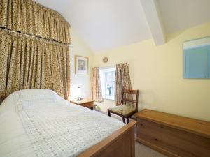 a bedroom with a bed and a chair and a window at Carpenter's Cottage in Matlock