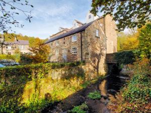 an old stone building with a bridge over a river at Carpenter's Cottage in Matlock