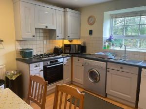 a kitchen with white cabinets and a dishwasher at Carpenter's Cottage in Matlock