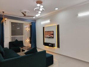 a living room with a couch and a tv at Staeg Meadow View 3BHK - 501 in Indore