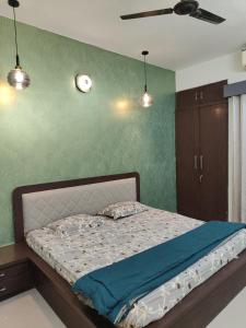 a bedroom with a bed with a green wall at Staeg Meadow View 3BHK - 501 in Indore